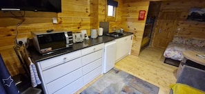 Cozinha compacta com micro-ondas, torradeira e cafeteira em bancada preta.