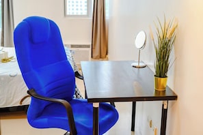 A room with a blue chair, a small table with a mirror, and a potted plant. - City Comfort at Seibu Tower (Taguig City)