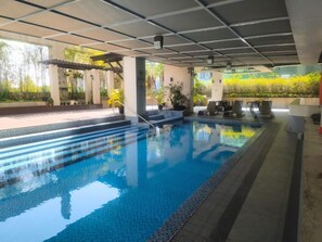 An indoor swimming pool with steps leading into it, surrounded by potted plants and outdoor greenery. - Modern Stay at Seibu Tower (Taguig City)