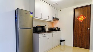 A compact kitchen with a stainless steel refrigerator, white cabinets, a microwave, and a stove. - City Comfort at Seibu Tower (Taguig City)