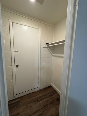 A narrow hallway with a white door, a wooden floor, and a white shelf against the wall. - Charming studio with AC in the heart of Little Rock (Little Rock)