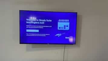 A television screen displaying a welcome message for Simply Suite Mockingbird A10, with options to select a checkout date and a note about terms and privacy policy.