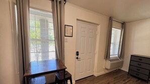 A room with a wooden desk, two chairs, a radiator, a door, and a dresser. - Charming studio with AC in the heart of Little Rock (Little Rock)