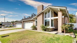 Ein zweistöckiges Haus mit Garage, überdachter Veranda und gepflegtem Rasen.