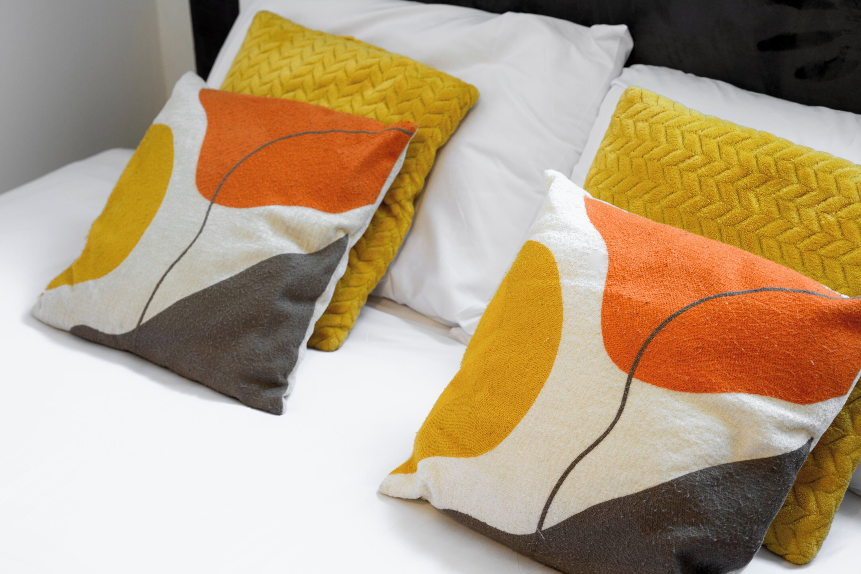 Een bed met twee kussens met abstracte patronen.
