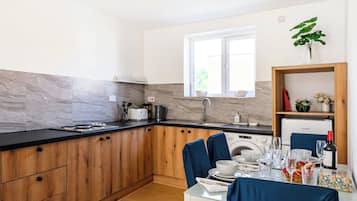 Eine moderne Küche mit Holzausstattung, einem eingebauten Backofen und einem Essbereich mit Tisch für zwei Personen.