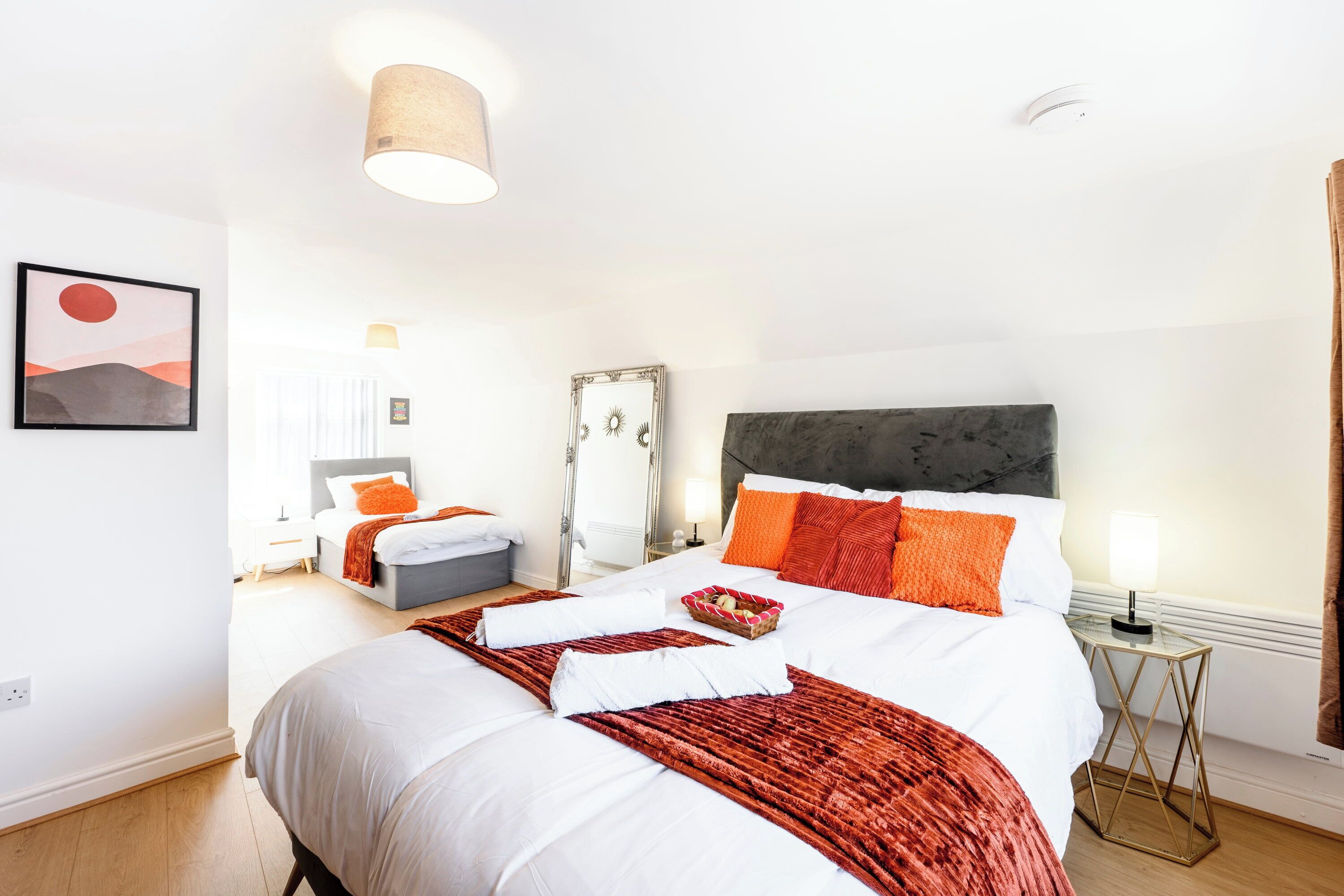 Ein Hotelzimmer mit einem großen Bett, einem Nachttisch, einem Spiegel und einer Wandlampe.