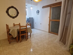 A dining area with a table set for four, a mirror on the wall, and a sliding door leading to another room. - Anir House (Tanger)