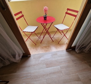 A small outdoor seating area with a table and two chairs, a potted plant, and a tiled floor. - Anir House (Tanger)