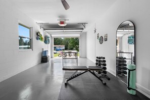 Ein Fitnessstudio mit Langhantelbank, Kurzhanteln und Spiegel.