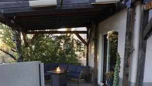 Ein Bereich mit Whirlpool, Feuerstelle, Sitzgelegenheiten und Topfpflanzen.