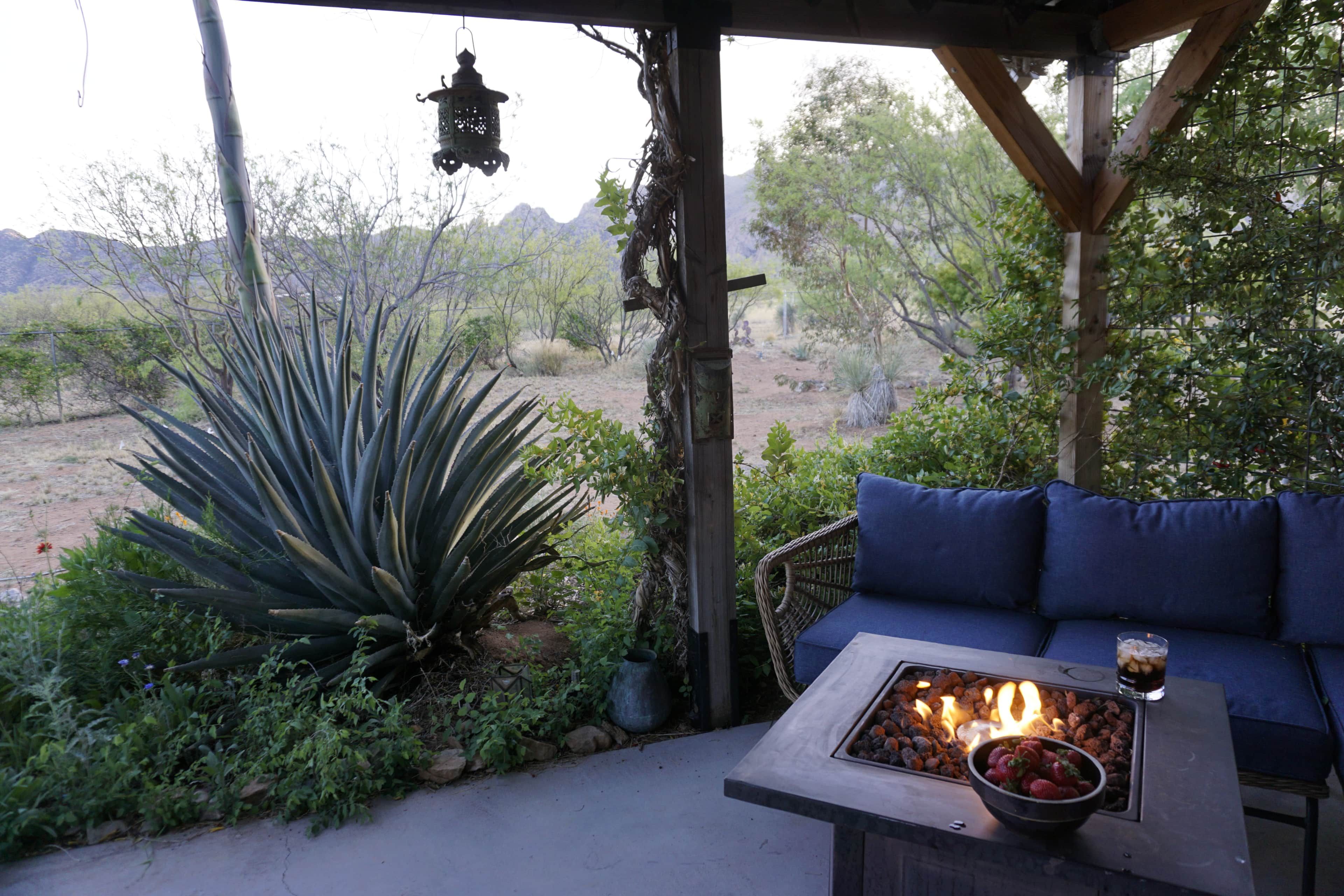 A covered outdoor seating area with a fire feature and a view of the desert landscape.