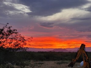 Ein Sonnenuntergang mit Bergen im Hintergrund und einem Bagger im Vordergrund.