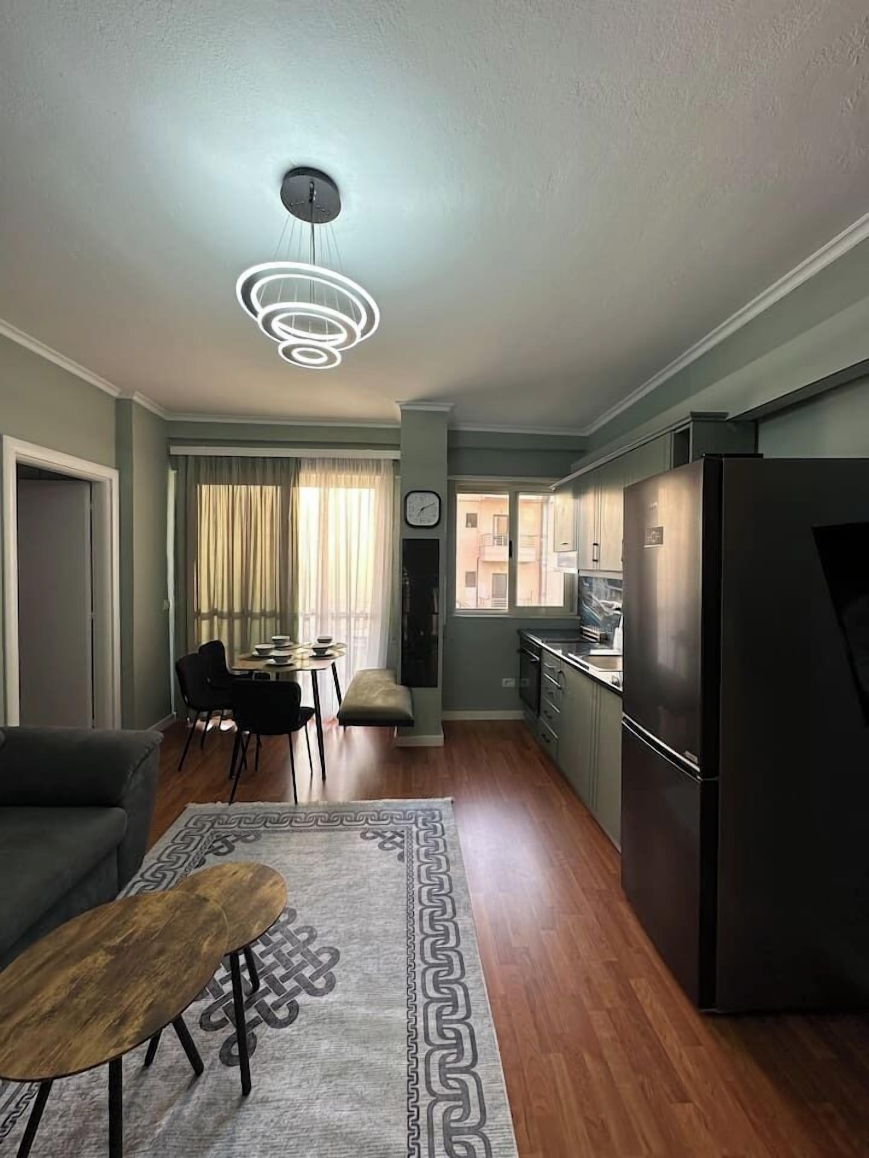 A compact living space with a dining area, kitchenette, and a modern ceiling light fixture.