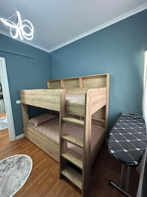 A bunk bed with a ladder, a small table with a patterned seat, and a hanging light fixture. - Olive apartment by TOK (Durrës)