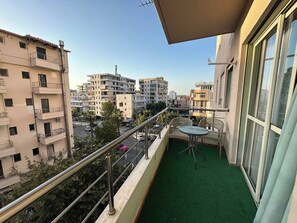 A balcony with a green artificial turf, a table, and chairs. - Olive apartment by TOK (Durrës)