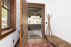 A wooden door leading to a stone-walled outdoor area with a bench and a rug inside. - 6-bedroom Ski-in/Ski-Out Luxury Mountain Retreat with Spanish Peaks Views (Big Sky)