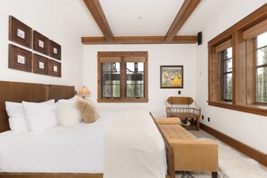 A bedroom with a large bed, a bench, a table, and a painting. - 6-bedroom Ski-in/Ski-Out Luxury Mountain Retreat with Spanish Peaks Views (Big Sky)