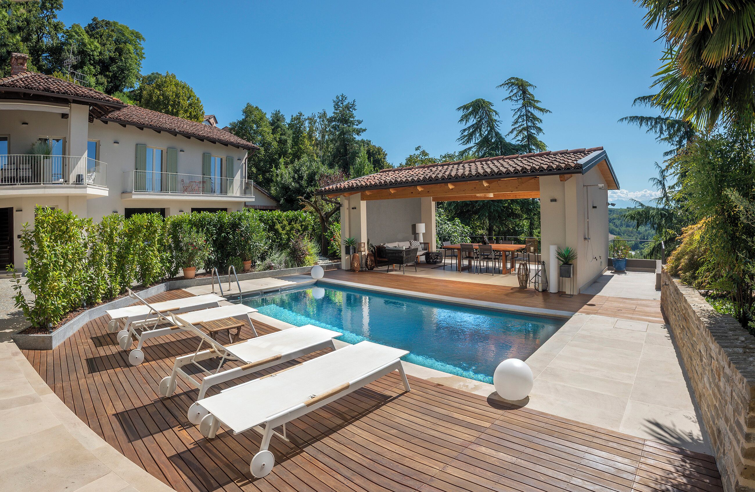 Une piscine avec des chaises longues, un patio couvert et une vue sur les montagnes.