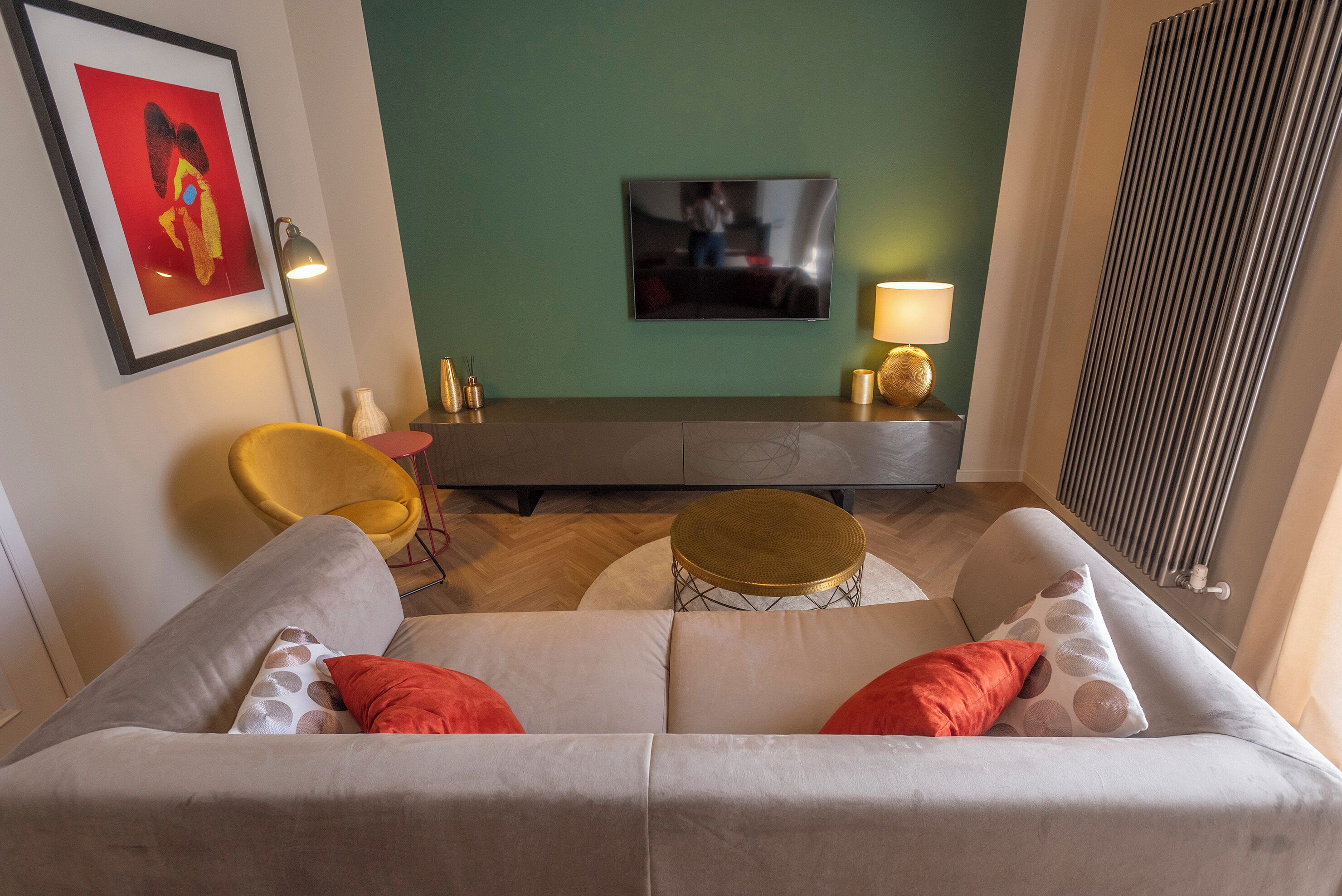 A living room with a sofa, a TV mounted on the wall, a lamp, and a chair.