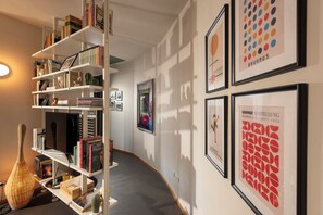 Eine Galerie mit gerahmten Kunstwerken und Bücherregalen, gefüllt mit Büchern und Dekorationsobjekten.