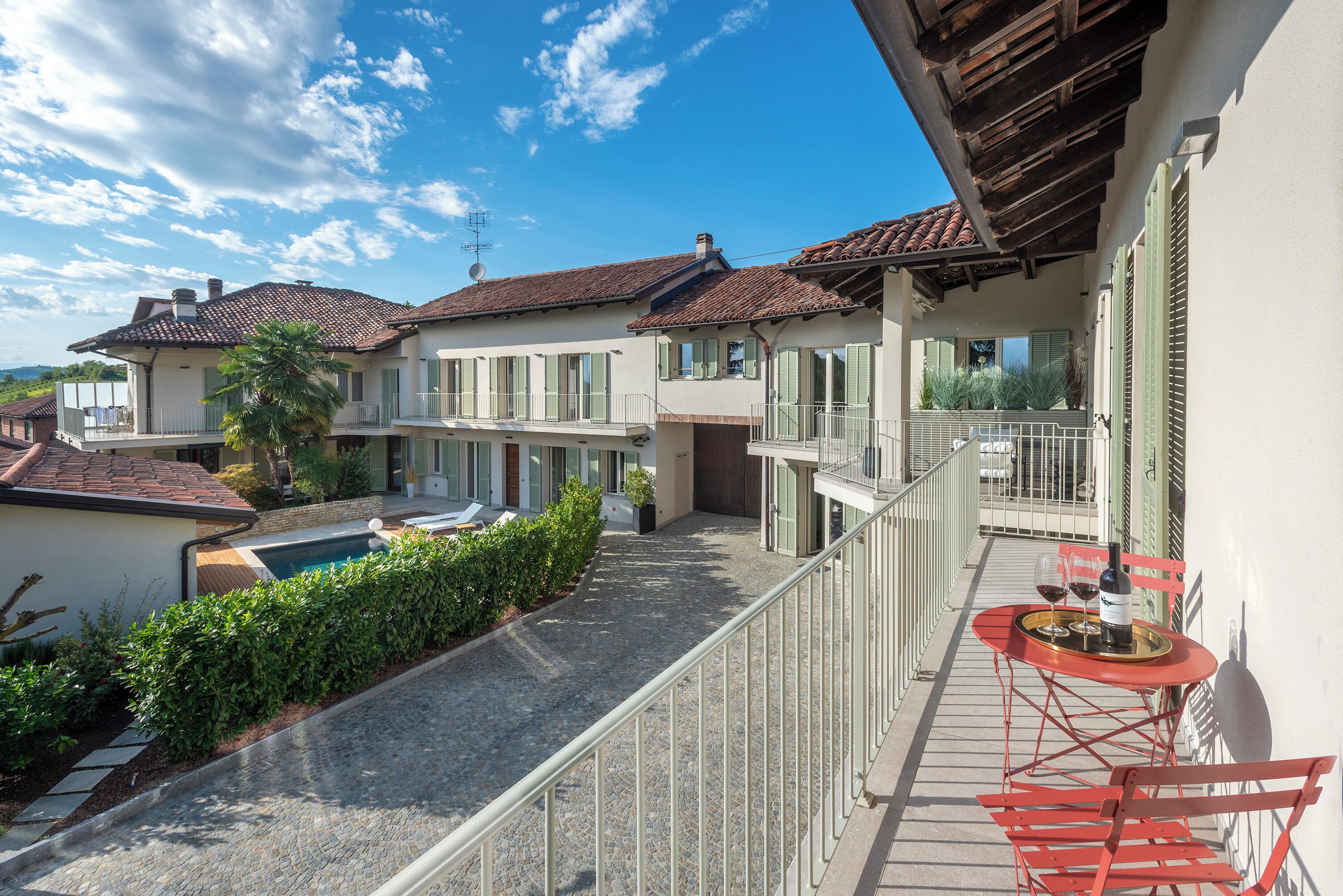 A residential property with a swimming pool, a balcony with a table and chairs, and a view of neighboring houses.