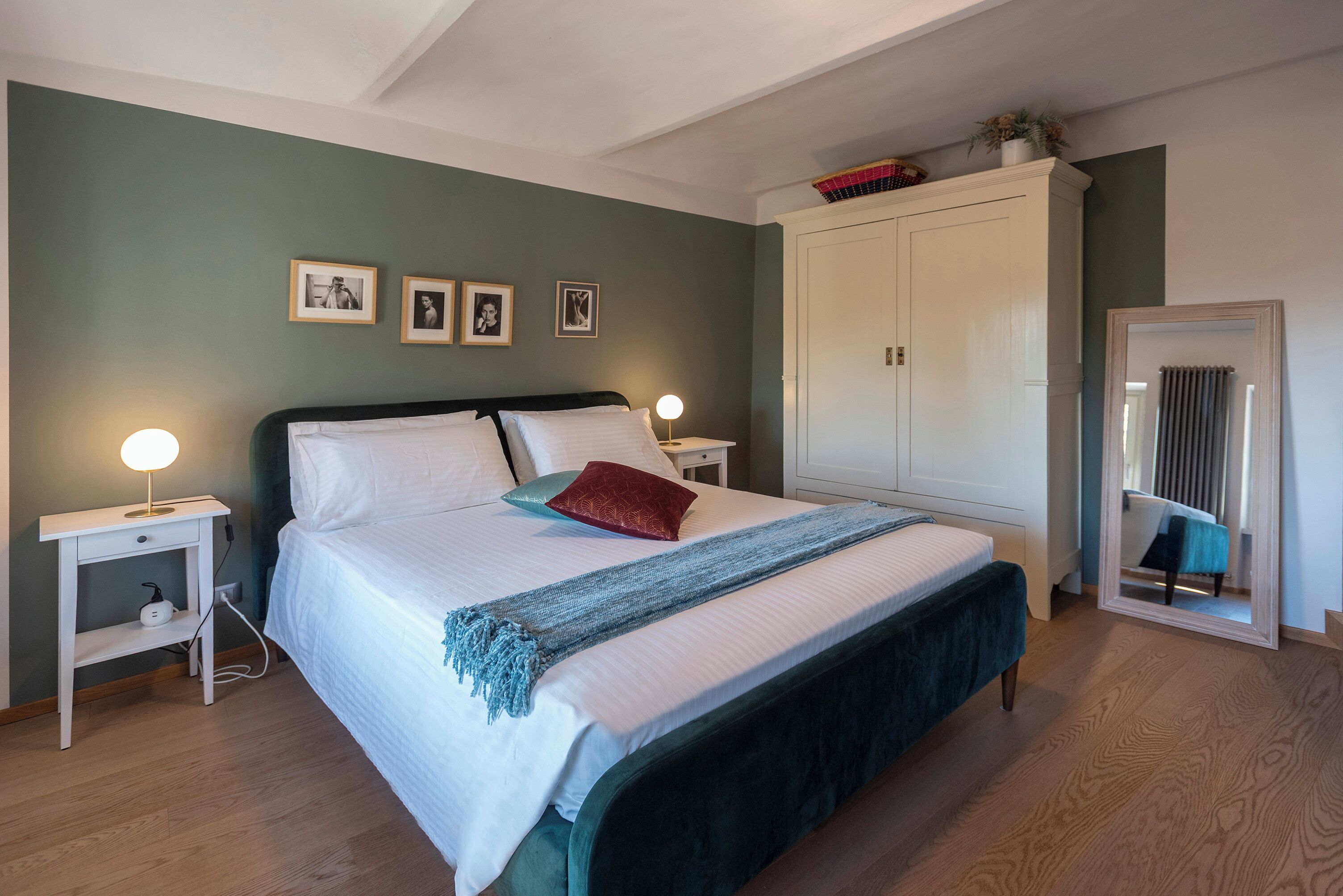 A bedroom with a bed, bedside tables, a wardrobe, and framed pictures on the wall.