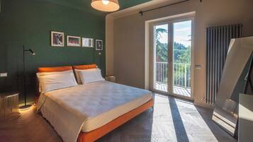 Ein Schlafzimmer mit Bett, Stehlampe, Heizkörper und einem Balkon mit Aussicht.