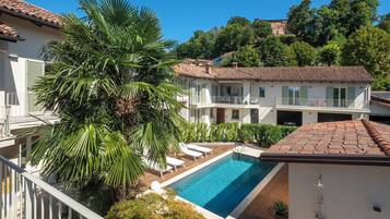Zona residencial con piscina, edificios blancos de techos rojos y abundante vegetación.