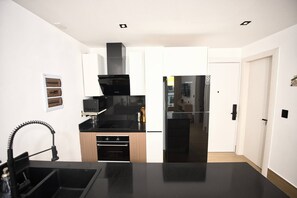 Eine moderne Küche mit schwarzer Arbeitsplatte, Edelstahlgeräten und einem Holzkorpus.