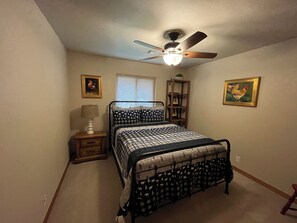 A bedroom with a bed, a nightstand, a lamp, a ceiling fan, and two wall-mounted pictures. - Classic lake lodge, boat launch, views, dock, blue water (Porum)