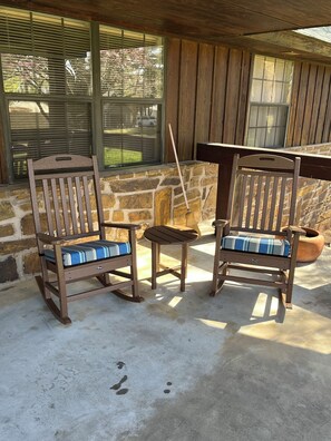 A patio area with two rocking chairs and a small table, set against a stone wall and wooden ceiling. - Classic lake lodge, boat launch, views, dock, blue water (Porum)