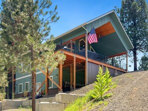 A two-story building with a balcony, an American flag, and a wooden deck. - Spacious 4BR Retreat on 1 Acre | Hot Tub, Pool Table & Near Lake Cascade (Cascade)