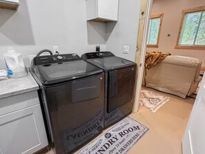 A laundry room with two front-loading washing machines, a white cabinet, and a sign indicating laundry services. - Spacious 4BR Retreat on 1 Acre | Hot Tub, Pool Table & Near Lake Cascade (Cascade)
