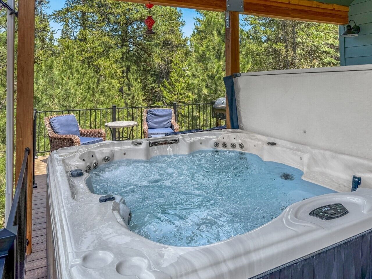 A hot tub on a wooden deck with a view of trees.