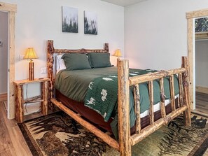 Ein Bett mit Holzrahmen, zwei Nachttische und eine grüne Bettdecke.
