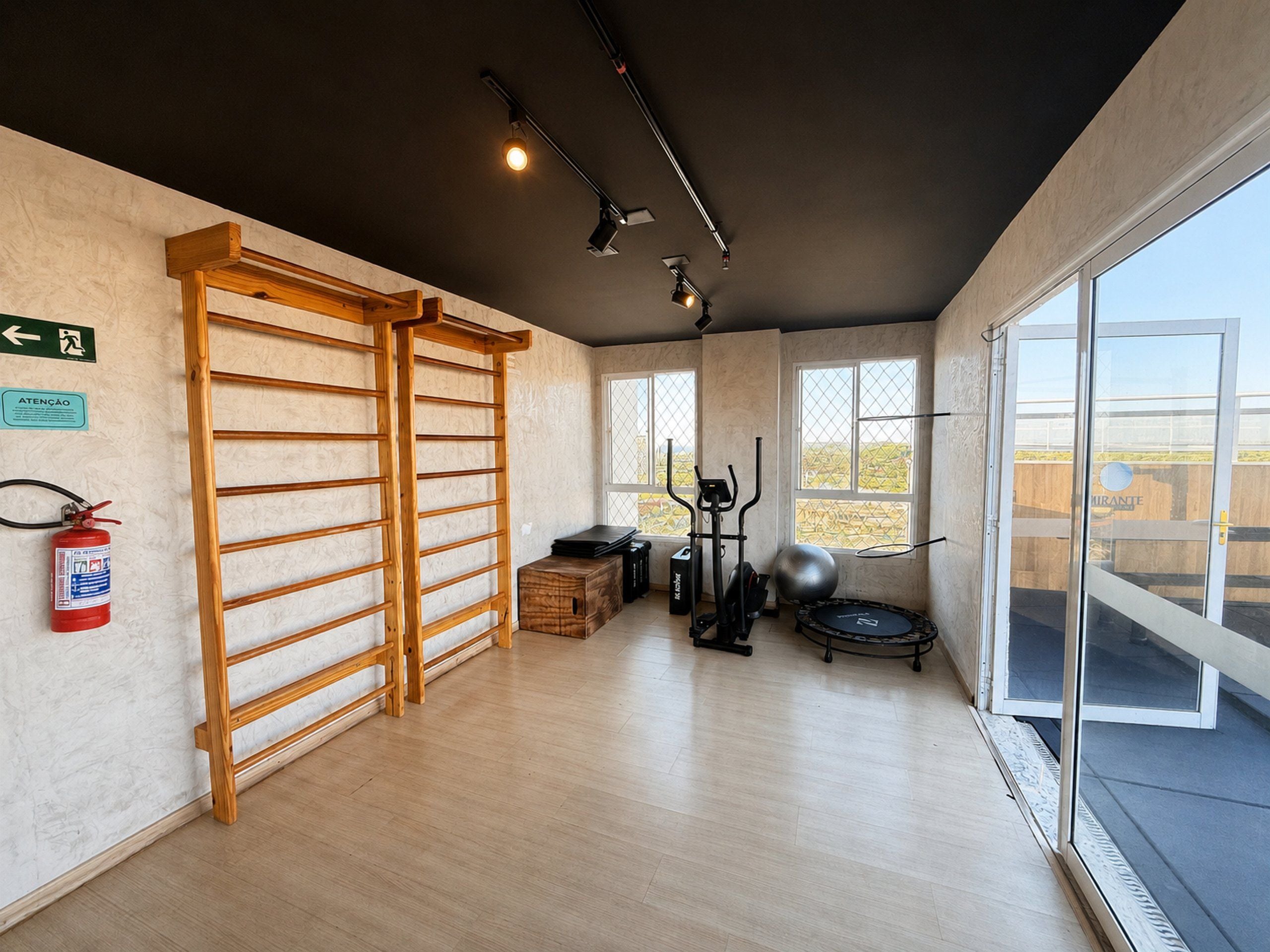 Een sportschool met trainingsapparatuur, een wand van houten latten en grote ramen.
