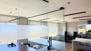 A modern office space with glass partitions, a conference table, and a seating area. - Hosts BR - Apto no Mirante Clube (Fortaleza)