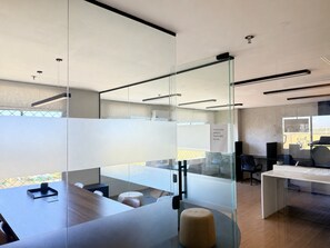 A modern office space with glass partitions, a conference table, and a seating area. - Hosts BR - Apto no Mirante Clube (Fortaleza)