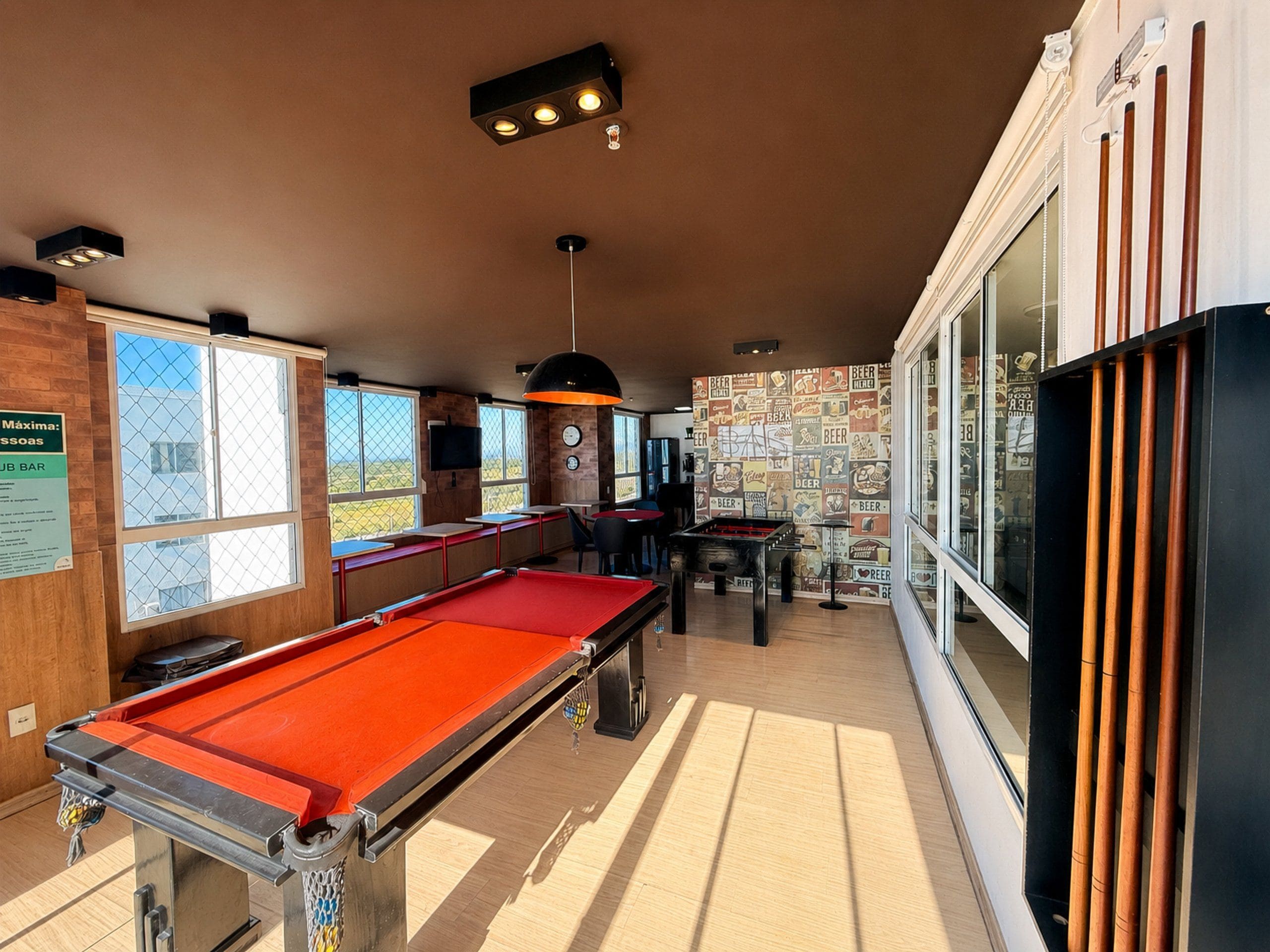 A billiards room with a pool table, seating area, and large windows.