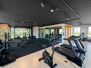 A gym with exercise equipment, a treadmill, and a mirrored wall. - Hosts BR - Apto no Mirante Clube (Fortaleza)