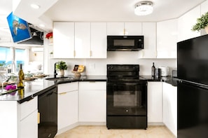 A modern kitchen with white cabinets, a black oven, a microwave, and a refrigerator. - Ilikai Hotel & Luxury Suites | 2 Marina View Condos Sleeps 10 | Car Incl. w/ 6+Nights | ML-4247 by KBM (Honolulu)