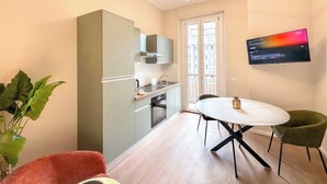 A compact kitchen with a dining area, a flat-screen TV, and a large window. - Flatsharing - Gioia Coral suite - 1 bedroom (Milan)