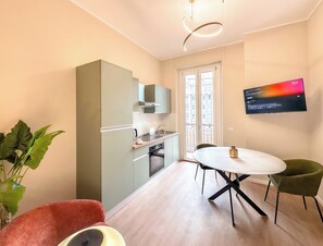 A compact kitchen with a dining area, a flat-screen TV, and a large window. - Flatsharing - Gioia Coral suite - 1 bedroom (Milan)