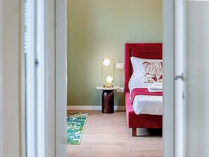 A bedroom with a bed, a bedside table with a mirror, and a green patterned rug. - Flatsharing - Gioia Coral suite - 1 bedroom (Milan)