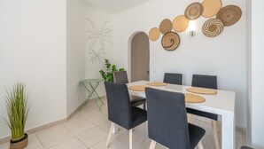 A dining area with a white table, black chairs, and woven placemats. - Apartment '6-person' with Shared Pool, Wi-Fi and Air Conditioning (Portimão)