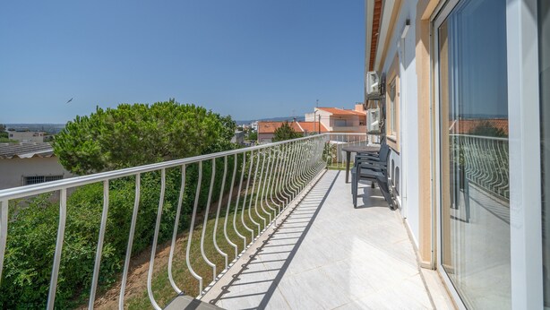 A balcony with a metal railing, a table, and chairs. - Apartment '6-person' with Shared Pool, Wi-Fi and Air Conditioning (Portimão)