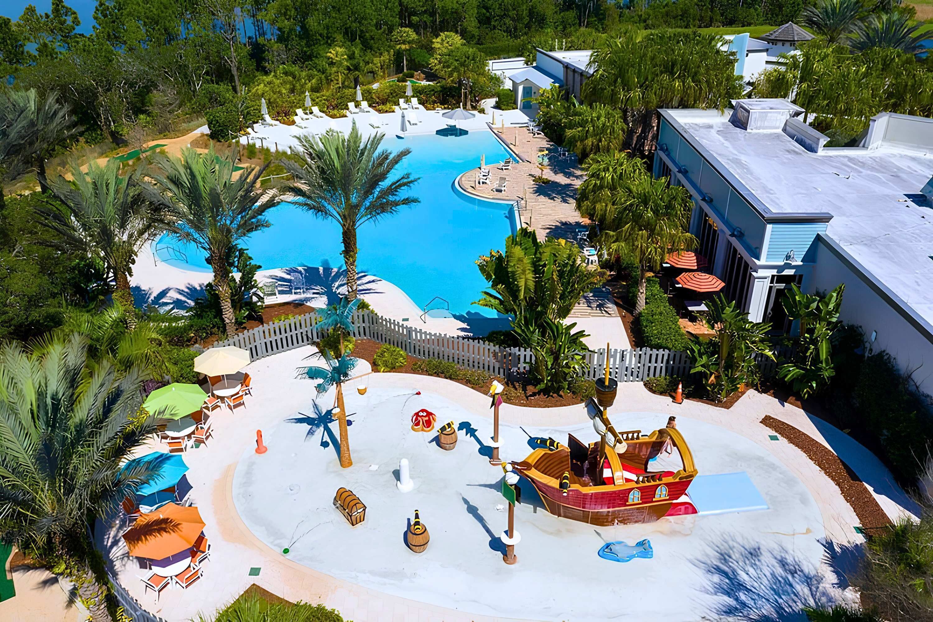 A resort with a large pool, palm trees, and a pirate-themed play area.