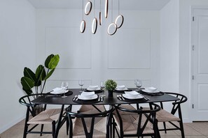 A dining room with a round table set for six, surrounded by black chairs with woven seats. - Disney Home w Lake View BBQ Patio & Resort Access (Davenport)