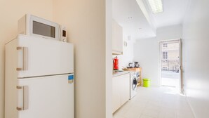 Une cuisine de taille réduite équipée d’un four à micro-ondes, d’un extincteur rouge et d’un lave-linge.